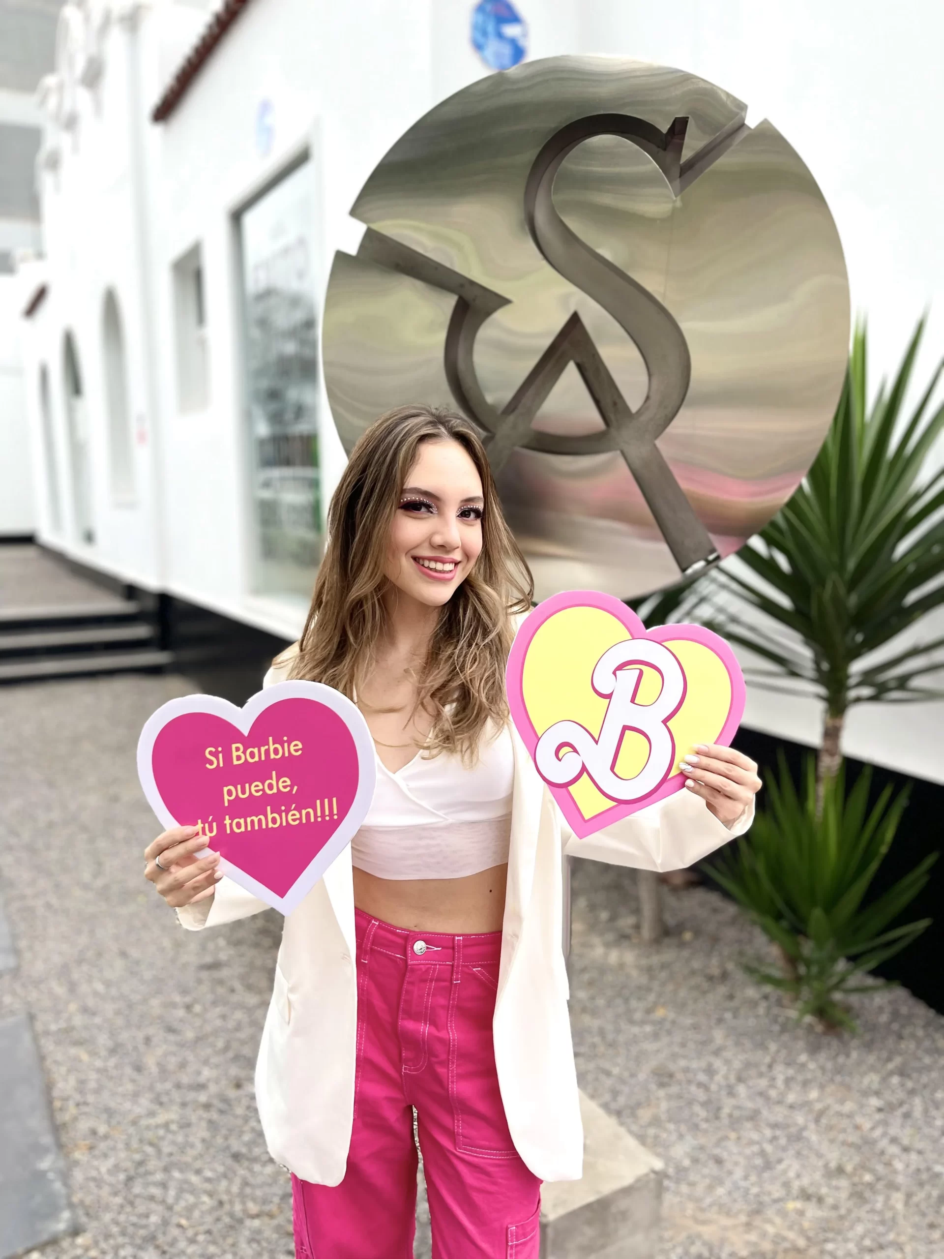 Estudiante sonriente con carteles de corazones de Barbie en frente de un símbolo de dólar artístico.